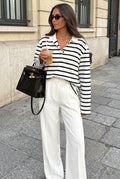 Sophie White striped polo shirt styled with white wide-leg trousers and a black handbag on a city sidewalk.