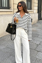 Sophie White striped polo shirt styled with white wide-leg trousers and a black handbag on a city sidewalk.