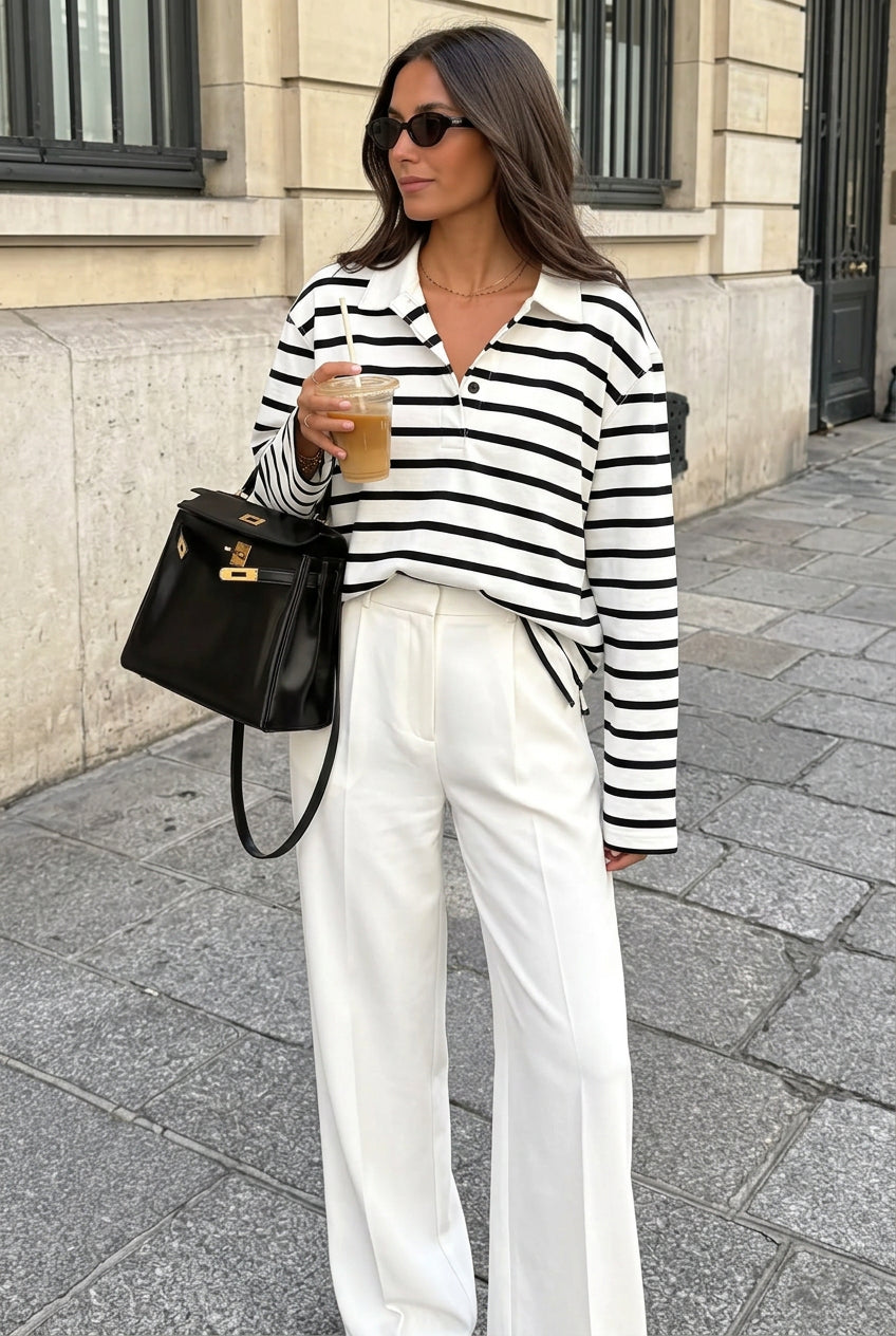Sophie White striped polo shirt styled with white wide-leg trousers and a black handbag on a city sidewalk.