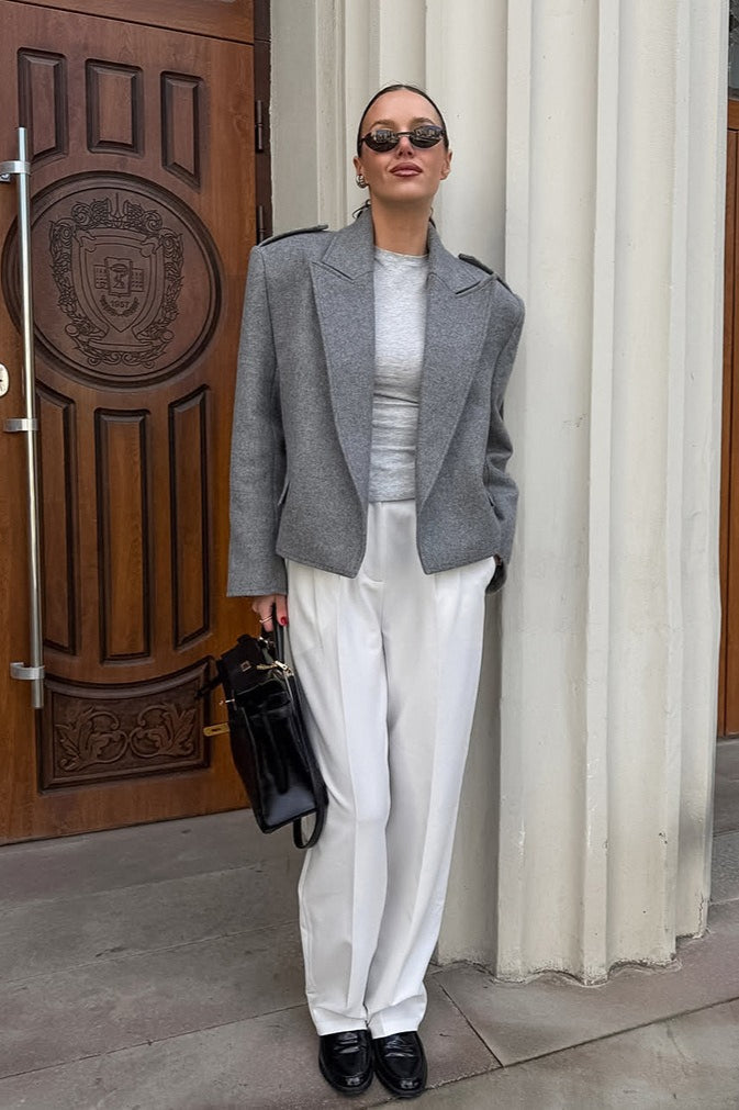 Tahlia Gray cropped blazer styled with a gray top, white pleated trousers and black loafers.