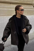 Tessa Brown faux suede jacket with faux shearling cuffs and collar worn open over a black top.