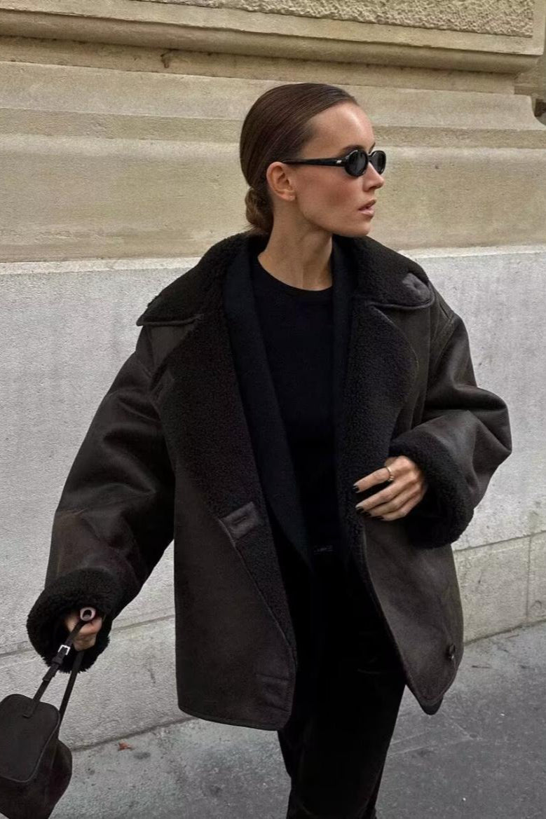 Tessa Brown faux suede jacket with faux shearling cuffs and collar worn open over a black top.