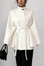 Vivian Off White belted cape coat featuring a stand collar, wide cape sleeves, self-tie belt, and softly flared silhouette