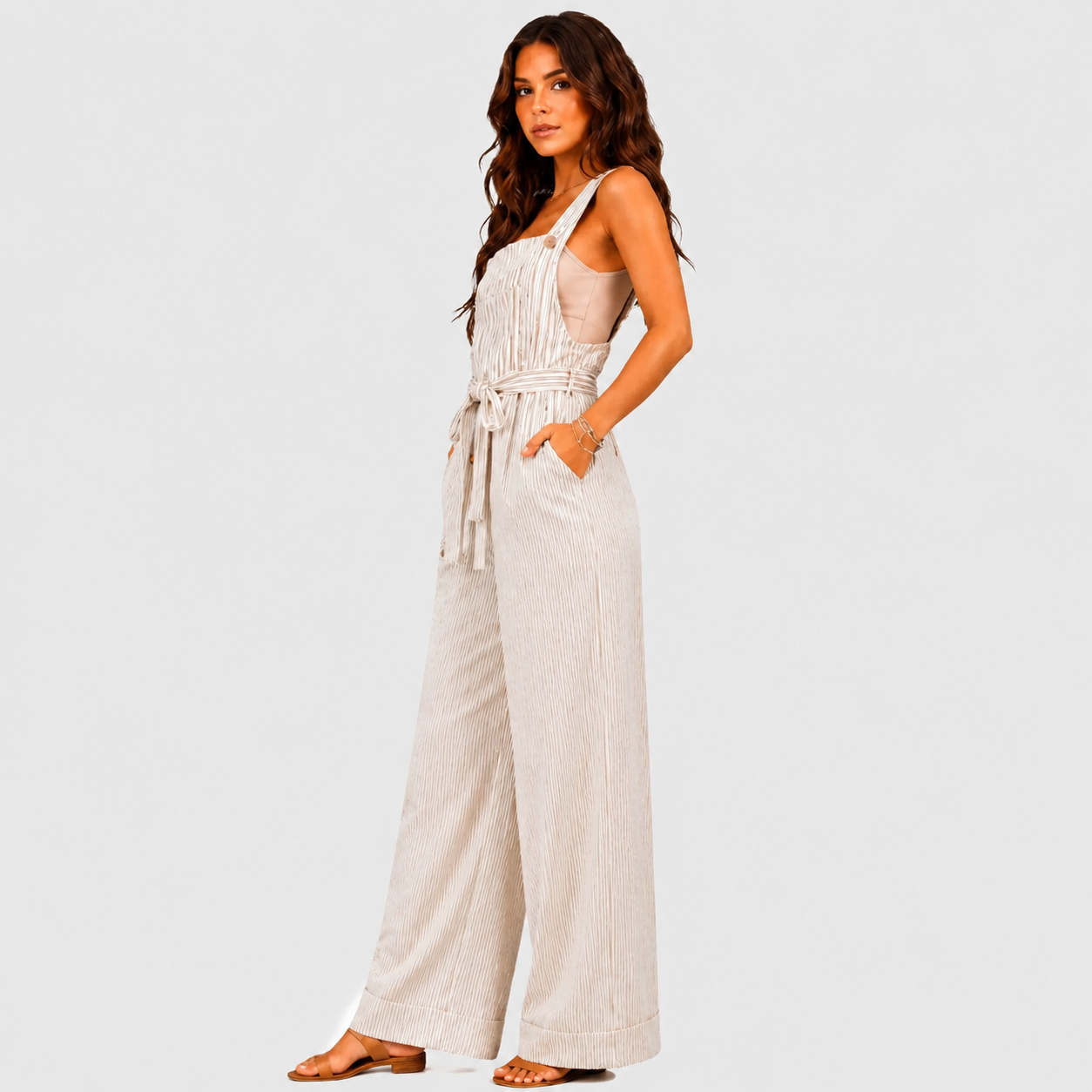 Side view of white striped wide leg jumpsuit with tie waist and sleeveless design by BELLA HUDSON
