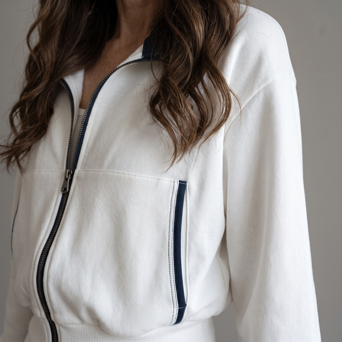 Close-up view of the Wilhelmina Two-Piece Set Striped Polo Wide-Leg in white, highlighting the polo collar, zip front, and contrast trim. By BELLA HUDSON.