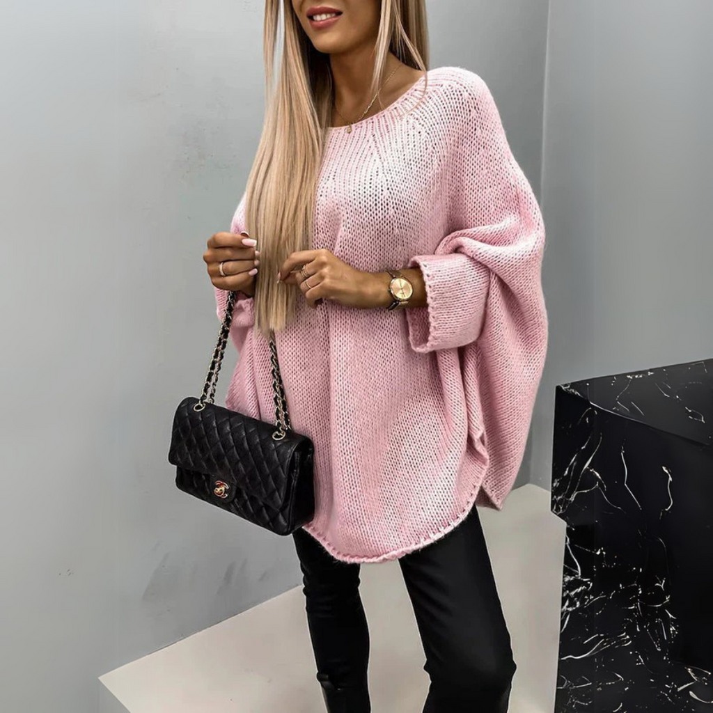 Front view of the Wilhelmine Sweater Oversized Batwing-Sleeve in pink, featuring a round neckline, wide batwing sleeves, textured knit fabric, asymmetrical hem, and a relaxed oversized silhouette. Designed by Bella Hudson.