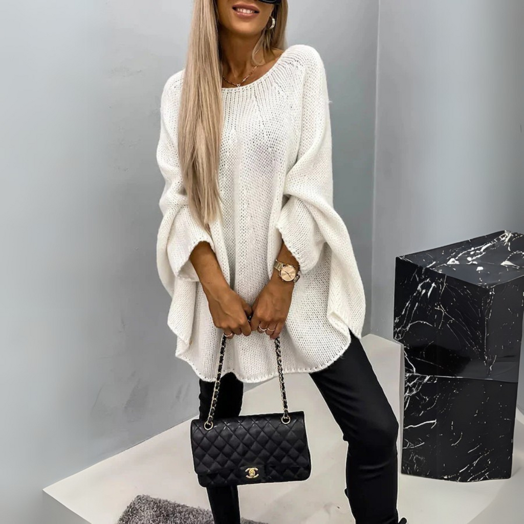 Front view of the Wilhelmine Sweater Oversized Batwing-Sleeve in white, featuring a round neckline, wide batwing sleeves, textured knit fabric, asymmetrical hem, and a flowing oversized silhouette. Designed by Bella Hudson.