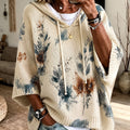Winifred Beige hooded floral cape sweater with drawstring hood, wide cape-style sleeves, floral detailing, and an oversized draped fit