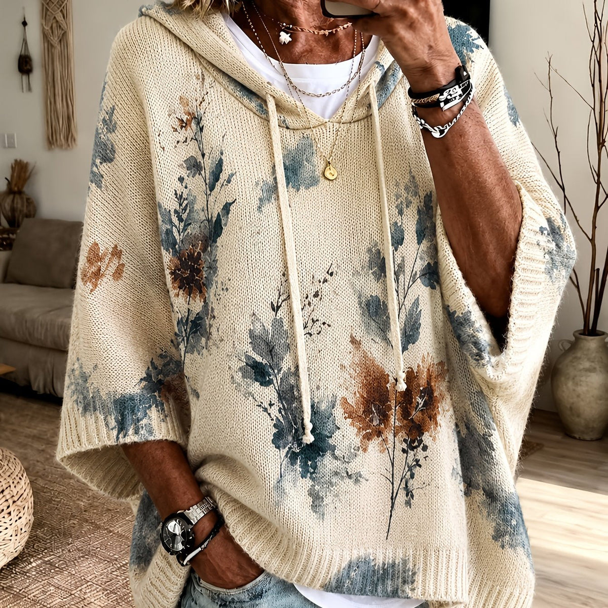 Winifred Beige hooded floral cape sweater with drawstring hood, wide cape-style sleeves, floral detailing, and an oversized draped fit