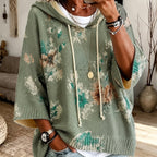 Winifred Green hooded floral cape sweater with floral detailing, drawstring hood, wide cape-style sleeves, and an easy draped fit