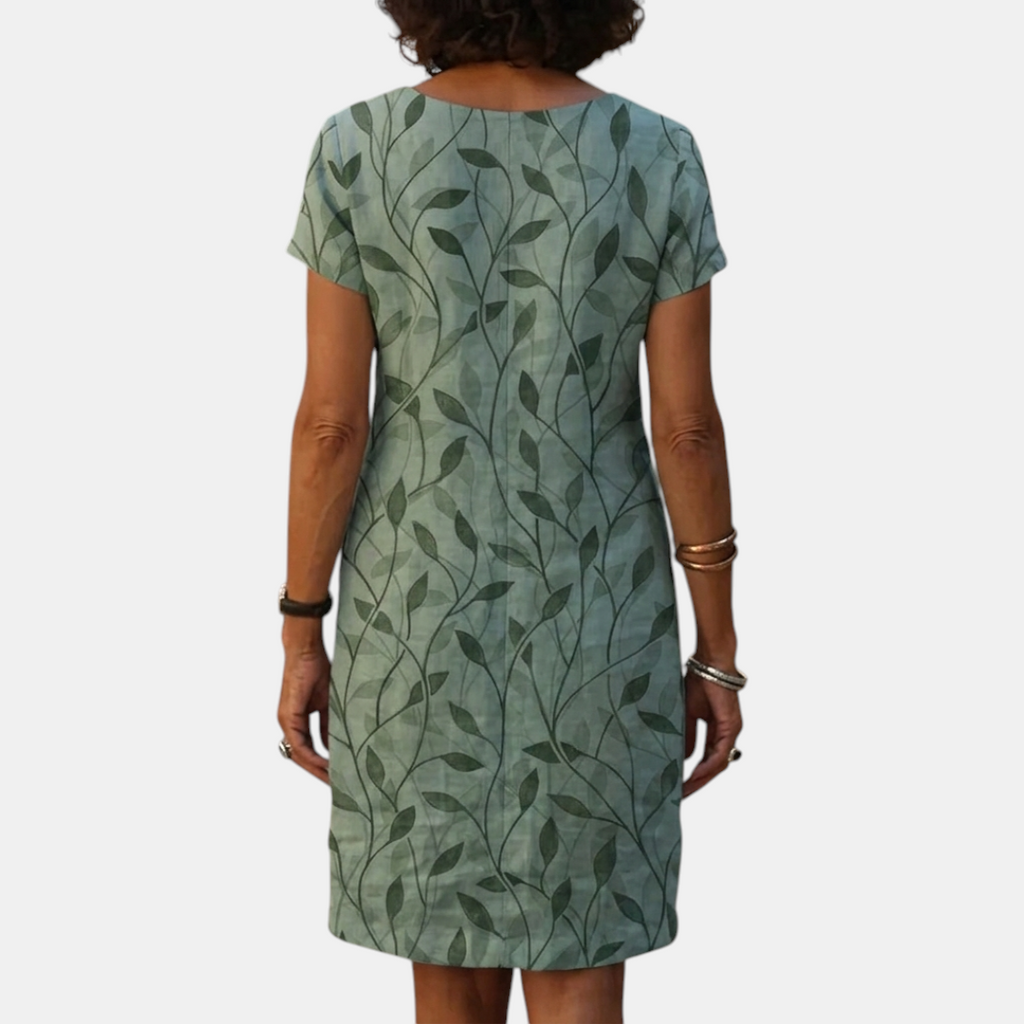 Back view of the Winnie Shift Dress Leaf-Print Lightweight Short-Sleeve in green, highlighting the relaxed shift silhouette, short sleeves, and all-over leaf print. Designed by Bella Hudson.