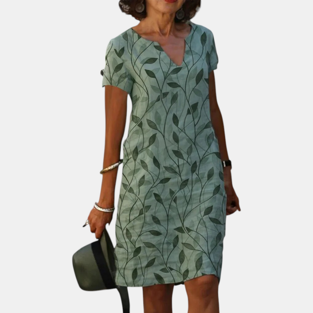 Front view of the Winnie Shift Dress Leaf-Print Lightweight Short-Sleeve in green, showcasing the V-neckline, short sleeves, practical side pockets, and relaxed everyday silhouette. Designed by Bella Hudson.