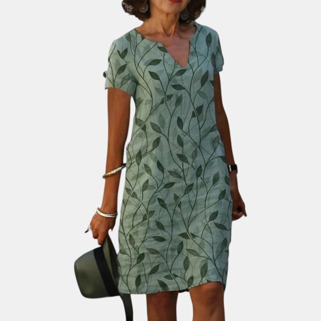 Front view of the Winnie Shift Dress Leaf-Print Lightweight Short-Sleeve in green, showcasing the V-neckline, short sleeves, practical side pockets, and relaxed everyday silhouette. Designed by Bella Hudson.
