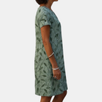 Side view of the Winnie Shift Dress Leaf-Print Lightweight Short-Sleeve in green, showcasing the relaxed fit, short sleeves, side pockets, and lightweight leaf-print fabric. Designed by Bella Hudson.