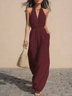 Front view of the Winnifred Maxi Dress Halter Open-Back in red, featuring a plunging V-neckline, halter-style bodice, defined waist, side pockets, and a flowing floor-length silhouette. Designed by Bella Hudson.