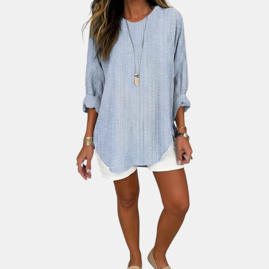 Front view of the Women's Boho Lightweight Blouse in blue, featuring a relaxed oversized fit, round neckline, rolled three-quarter sleeves, subtle textured fabric, and a curved high-low hem. Designed by Bella Hudson.