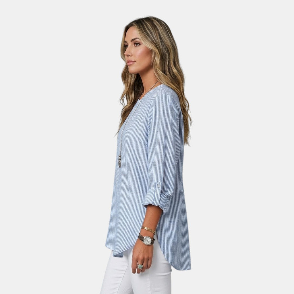 Side view of the Women's Boho Lightweight Blouse in blue, showcasing the relaxed silhouette, rolled sleeves, and flowing high-low hem for effortless everyday style. Designed by Bella Hudson.