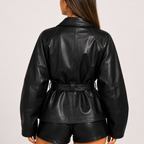 Back view of Women's Cropped Biker Style Faux Leather Jacket in Black showcasing the structured silhouette, wide sleeves, belted waist, and smooth faux leather texture designed by Bella Hudson.