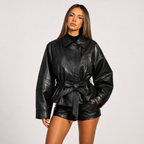 Front view of Women's Cropped Biker Style Faux Leather Jacket in black featuring an oversized silhouette, wide collar, belted waist, and premium faux leather finish designed by Bella Hudson.