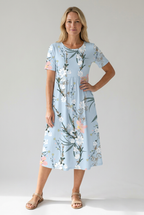Front view of light blue floral print midi dress with short sleeves, empire waist and pockets by BELLA HUDSON