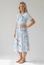 Side view of light blue floral print midi dress with short sleeves, empire waist and pockets by BELLA HUDSON