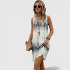 Walking view of the Zinnia A-Line Dress Sleeveless Ink-Wash-Print in white, showcasing the lightweight fabric, relaxed A-line silhouette, and blue ink-wash print in motion. Designed by Bella Hudson.